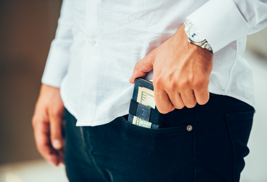 man putting slim leather wallet in his front pocket