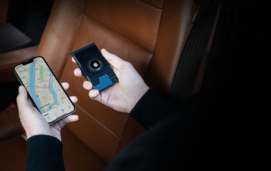 A close-up of hands, one holding an iPhone with the 'Find My Phone' app on the screen and the other holding Ekster's aluminum cardholder for AirTag.